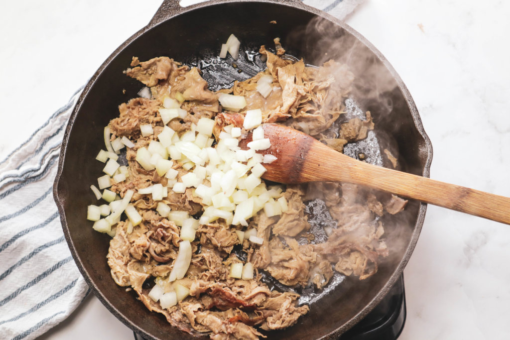 shaved steak cooked in a cast iron skillet with onions