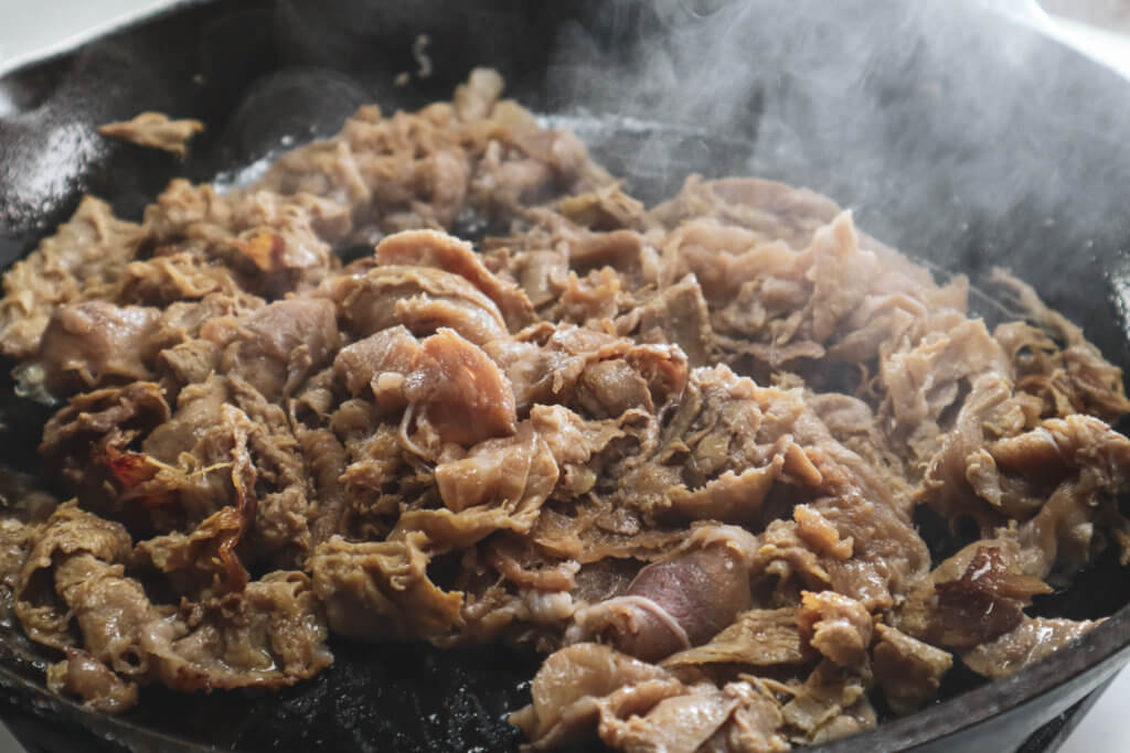 shaved steak cooking in a cast iron skillet