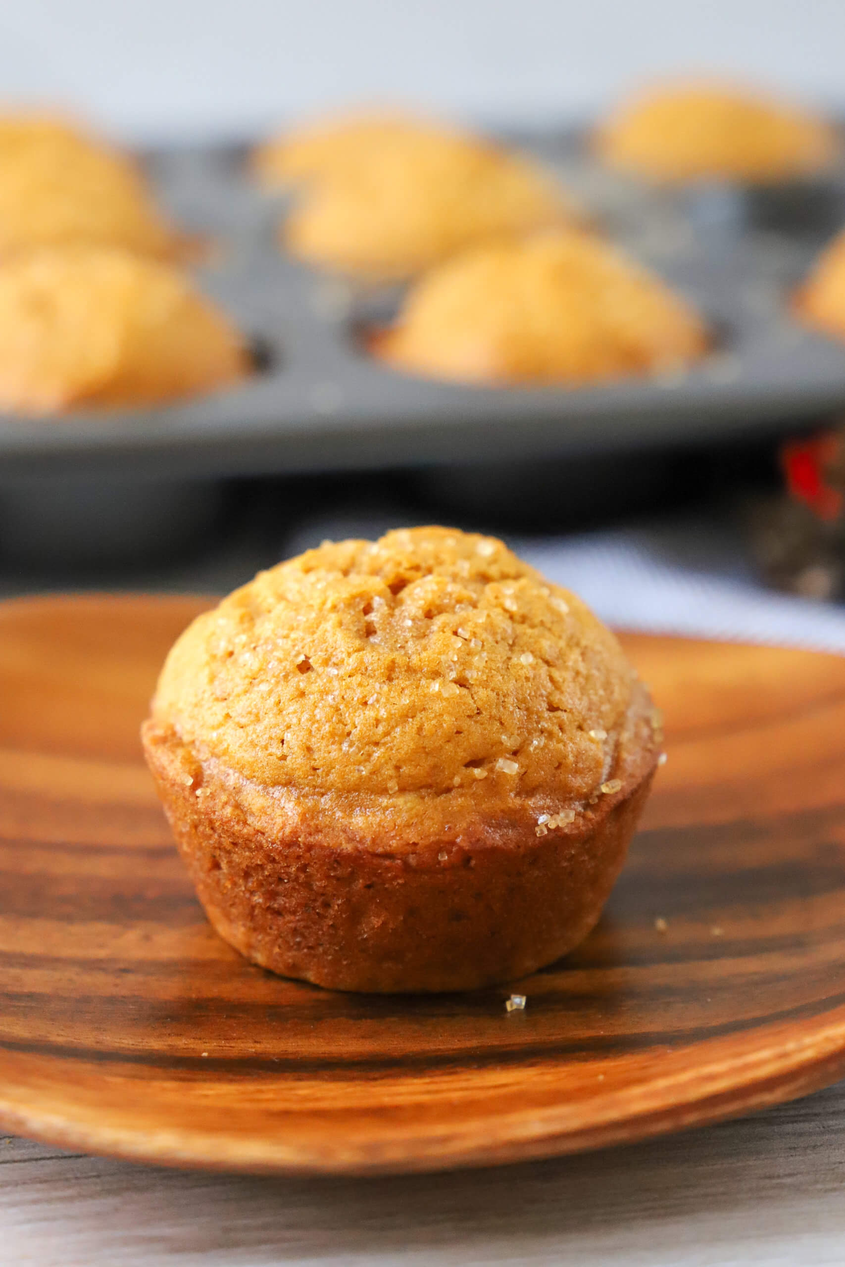 pumpkin muffin on plate with pan of muffins in the background