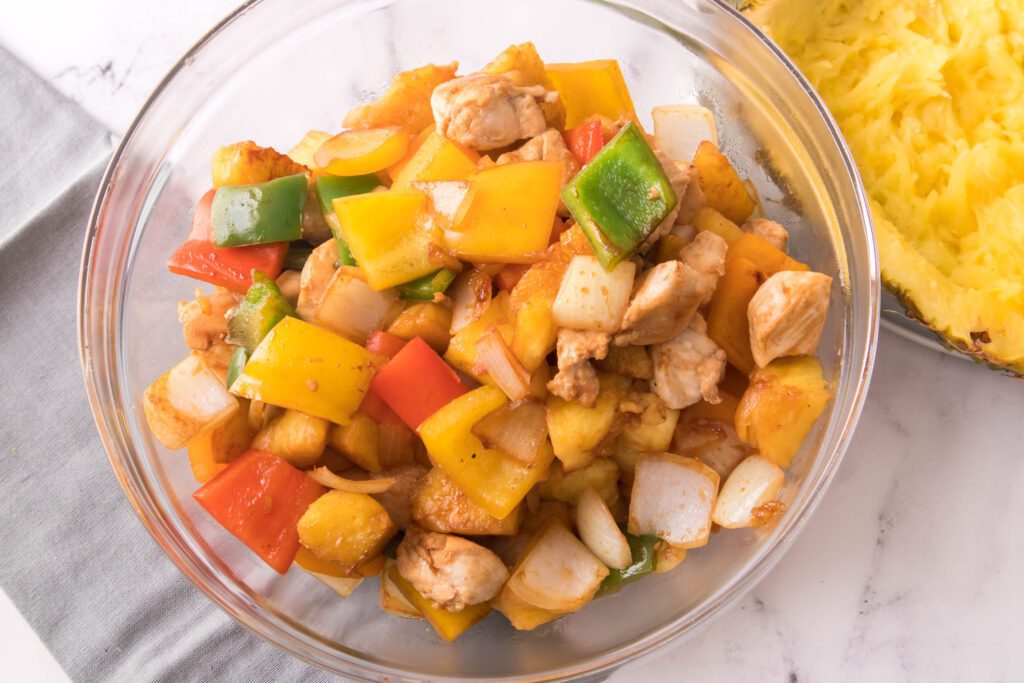 Overhead shot of chicken, pineapple chunks, bell peppers and onion in a bowl after coming off the grill