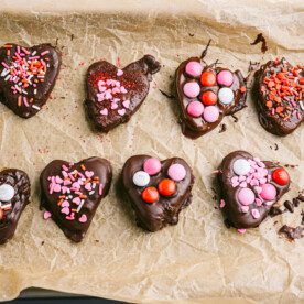 chocolate covered hearts on brown parchment paper on a baking sheet with sprinkles and M&m's
