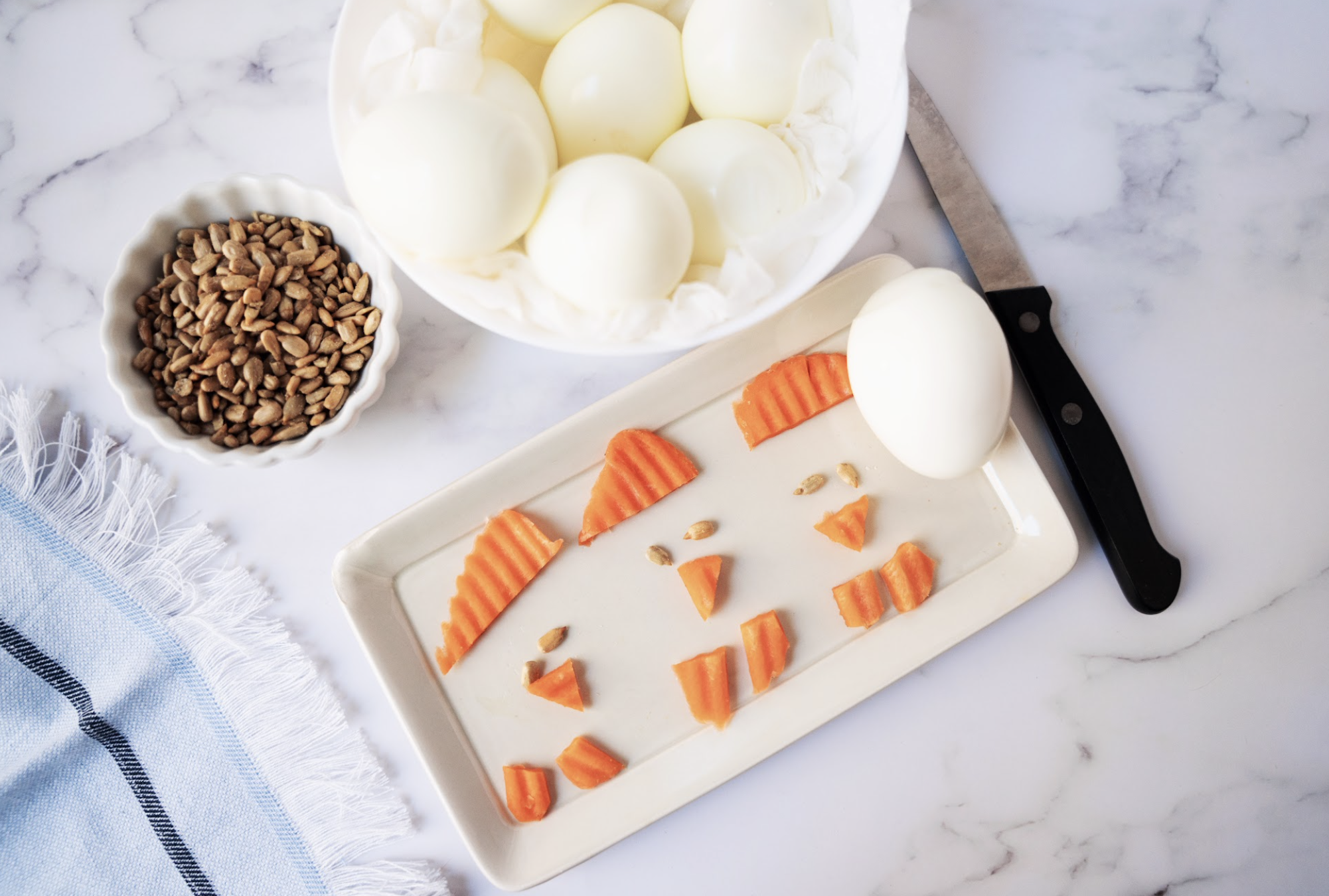 cut Carrot chips on a plate with hard boiled eggs and sunflower seeds in bowls