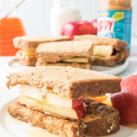 apple, peanut butter and honey sandwich on a white plate