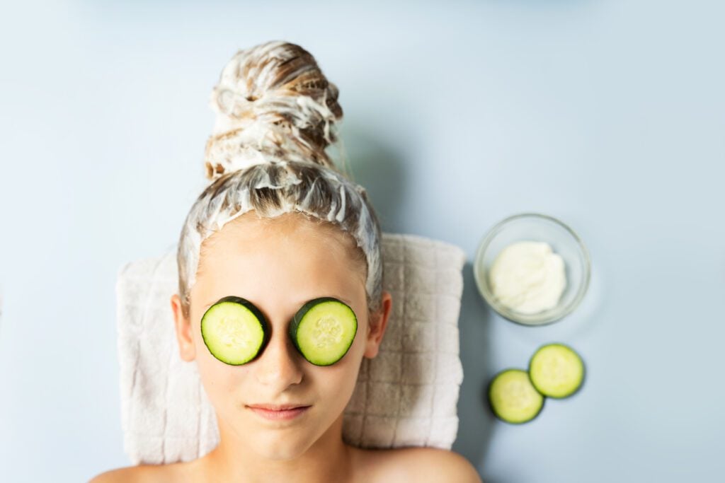 girl with cucumbers on her eyes and celery hair mask on her hair