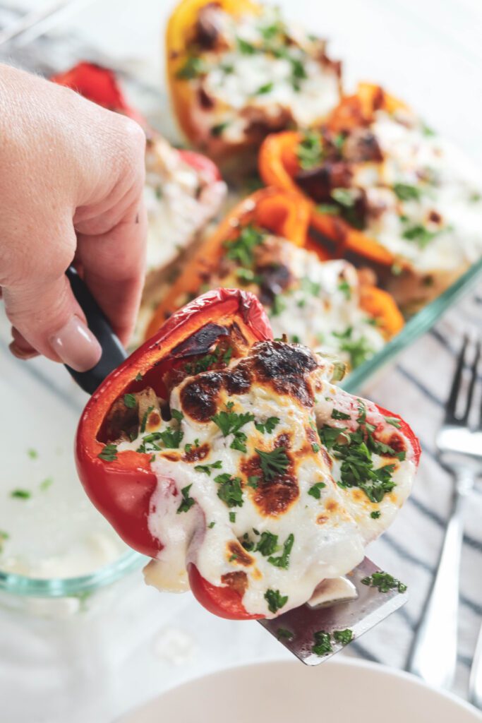 stuffed peppers on spatula and in pan