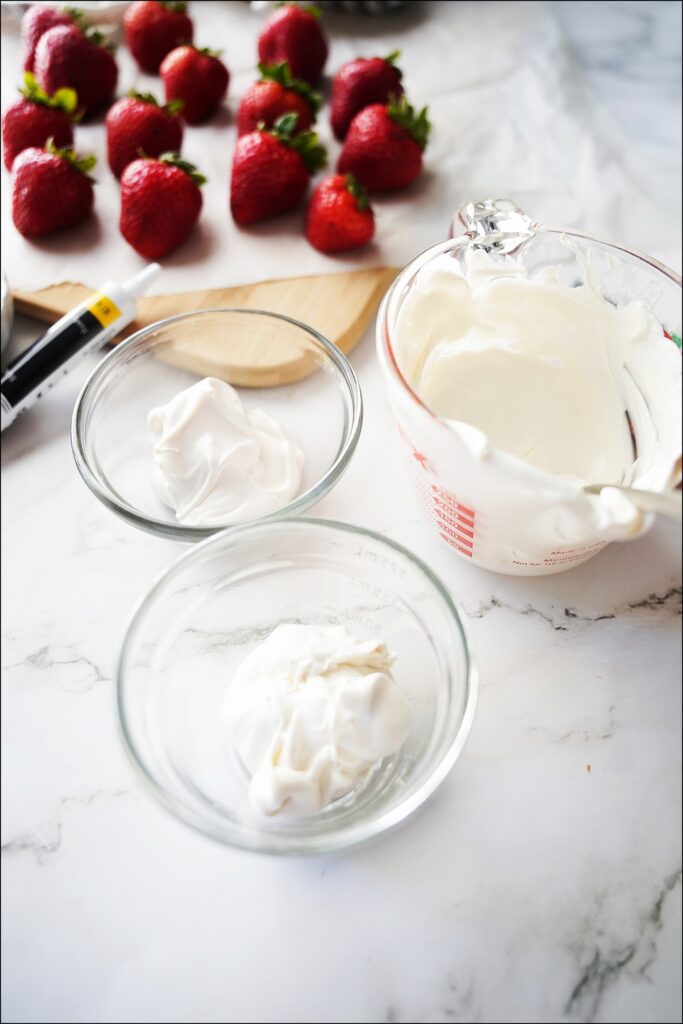 melted white chocolate divided into three bowls with strawberries in the background
