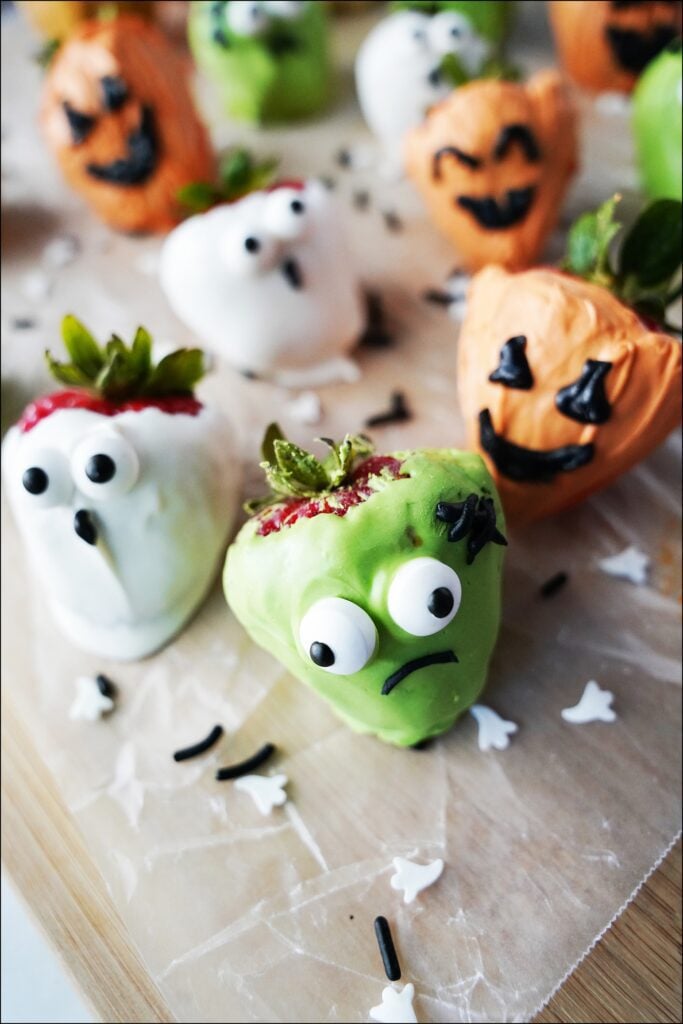 halloween chocolate covered strawberries made to look like frankenstein, a ghost and pumpkin