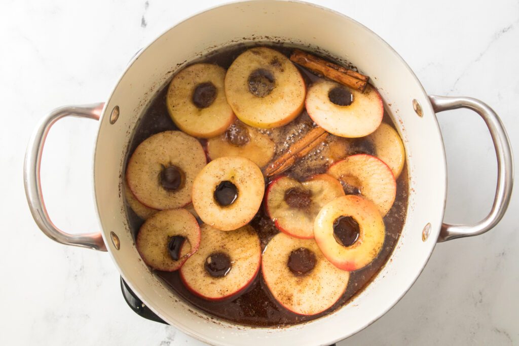 cinnamon sticks added to apple rings in skillet
