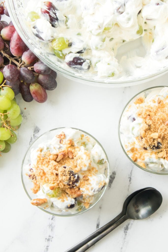 overhead shot of grape salad recipe in a glass bowl topped with brown sugar and walnuts
