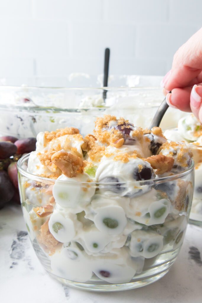 hand with spoon eating grape salad