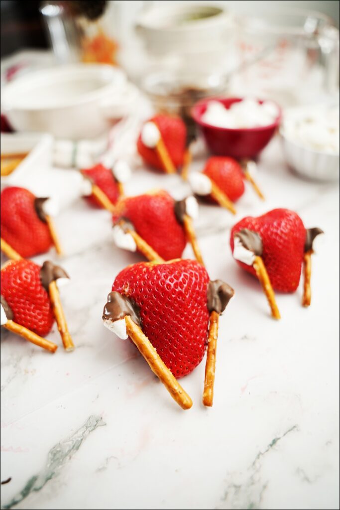 strawberries with melted chocolate that attaches mini marshmallows to a pretzel stick