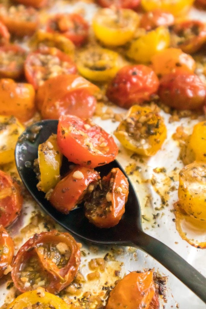 close up shot of spoon with cherry tomatoes that have been roasted in the oven