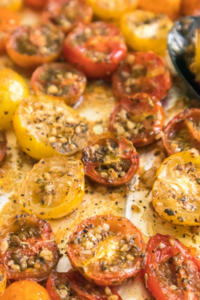 vertical close up shot of roasted cherry tomatoes on baking sheet with aluminum foil