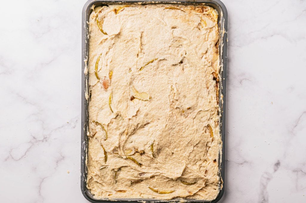 dough with apple pie filling topped with more dough on baking sheet