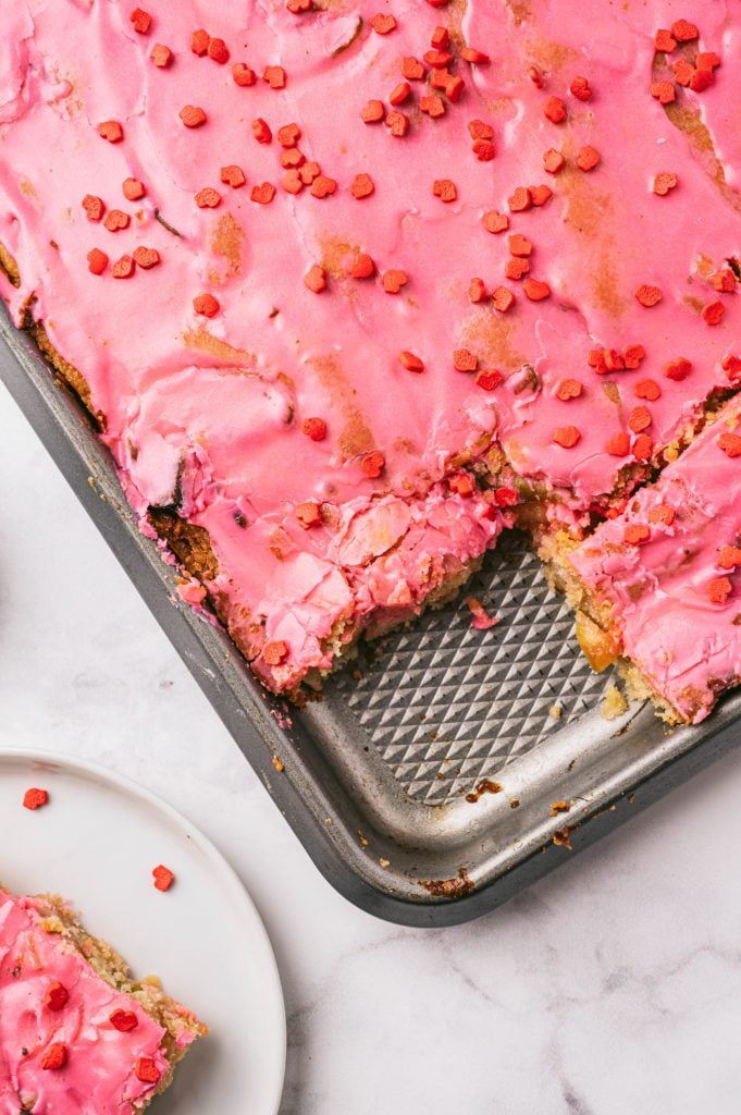 closeup vertical shot of apple slices with pink icing and valentine's sprinkles