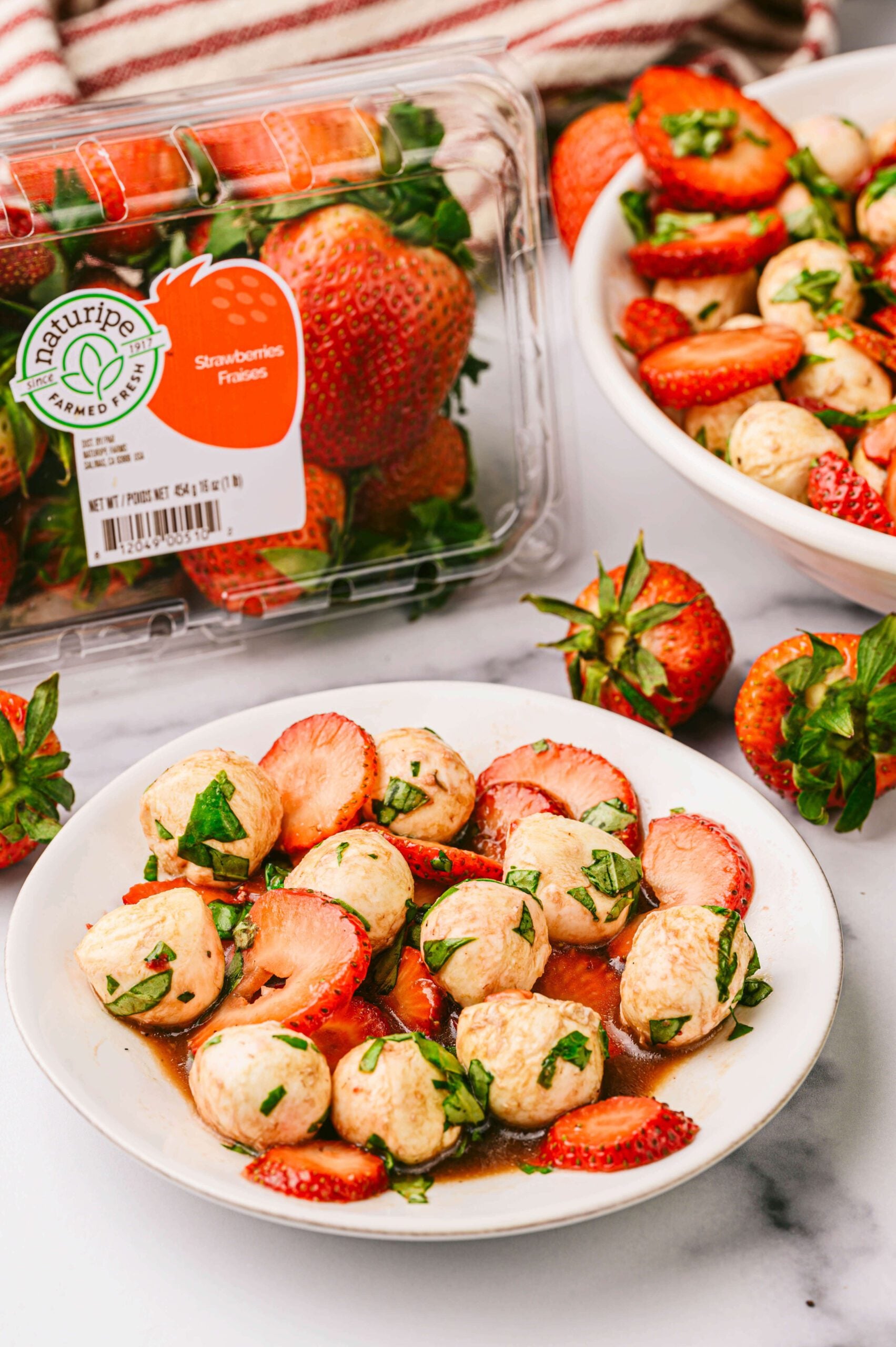 Bowl of strawberry caprese and Naturipe strawberries in background