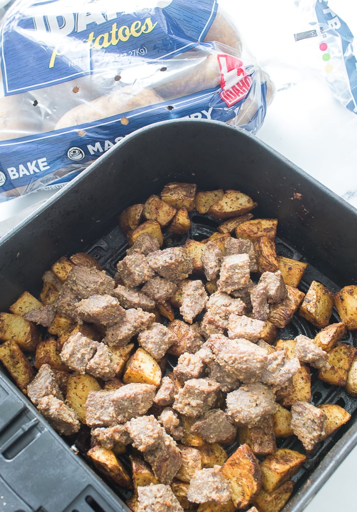 close up shot of potatoes and steak in air fryer
