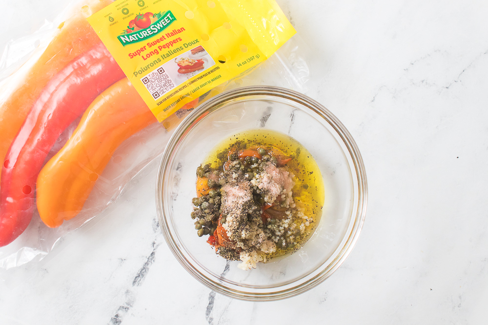 sweet peppers in glass bowl with olive oil, capers, garlic, salt and pepper