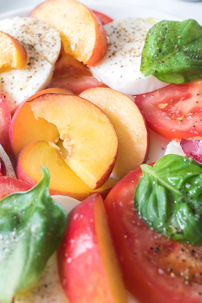 vertical close up shot of sliced Prima Peaches plated with caprese
