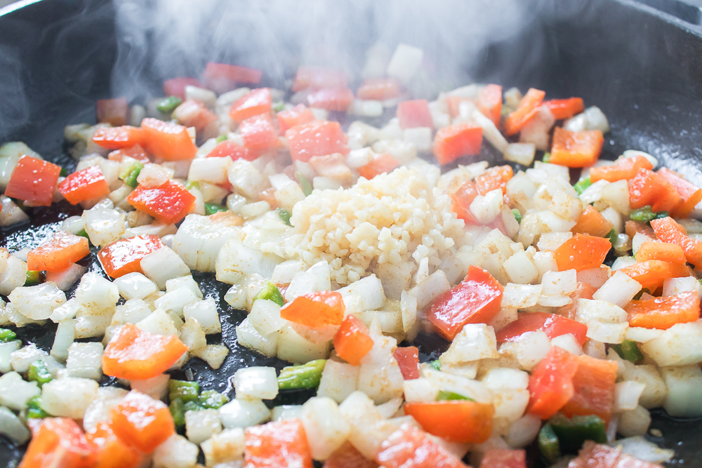 Adding in garlic to pan with onions and peppers