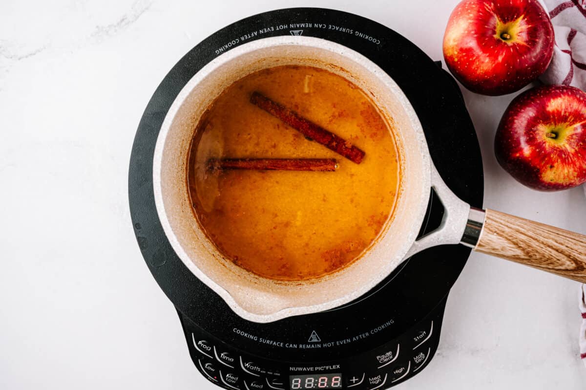 pan boiling apple cider, lmeon, honey and cinnamon stick