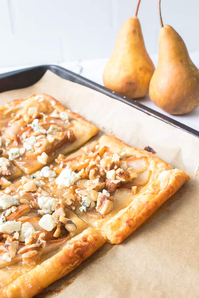 blue cheese and pear tart on baking sheet with two pears in background