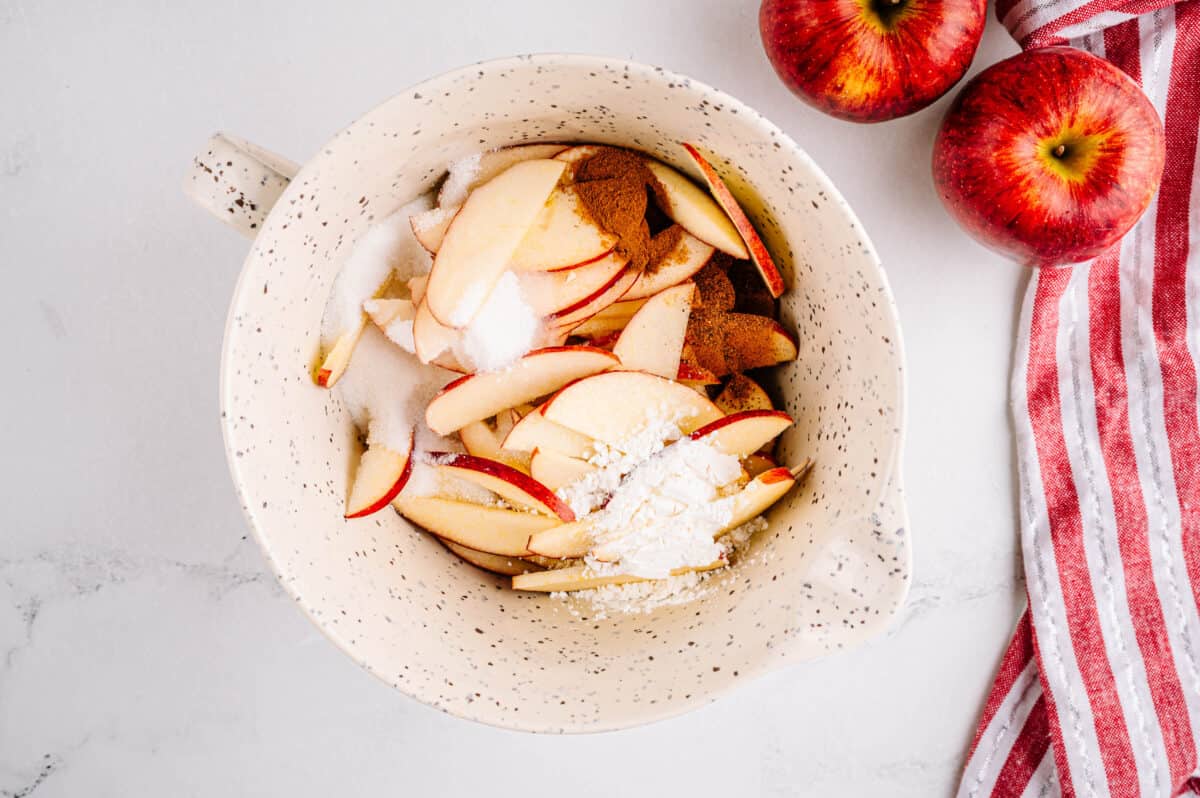 bowl with sliced apples, sugar, cinnamon, nutmeg, cornstarch and lemon juice