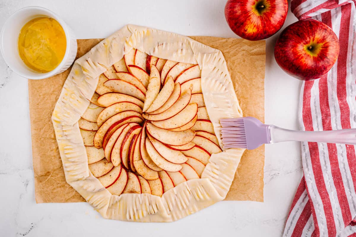 brush placing melted butter on pie crust