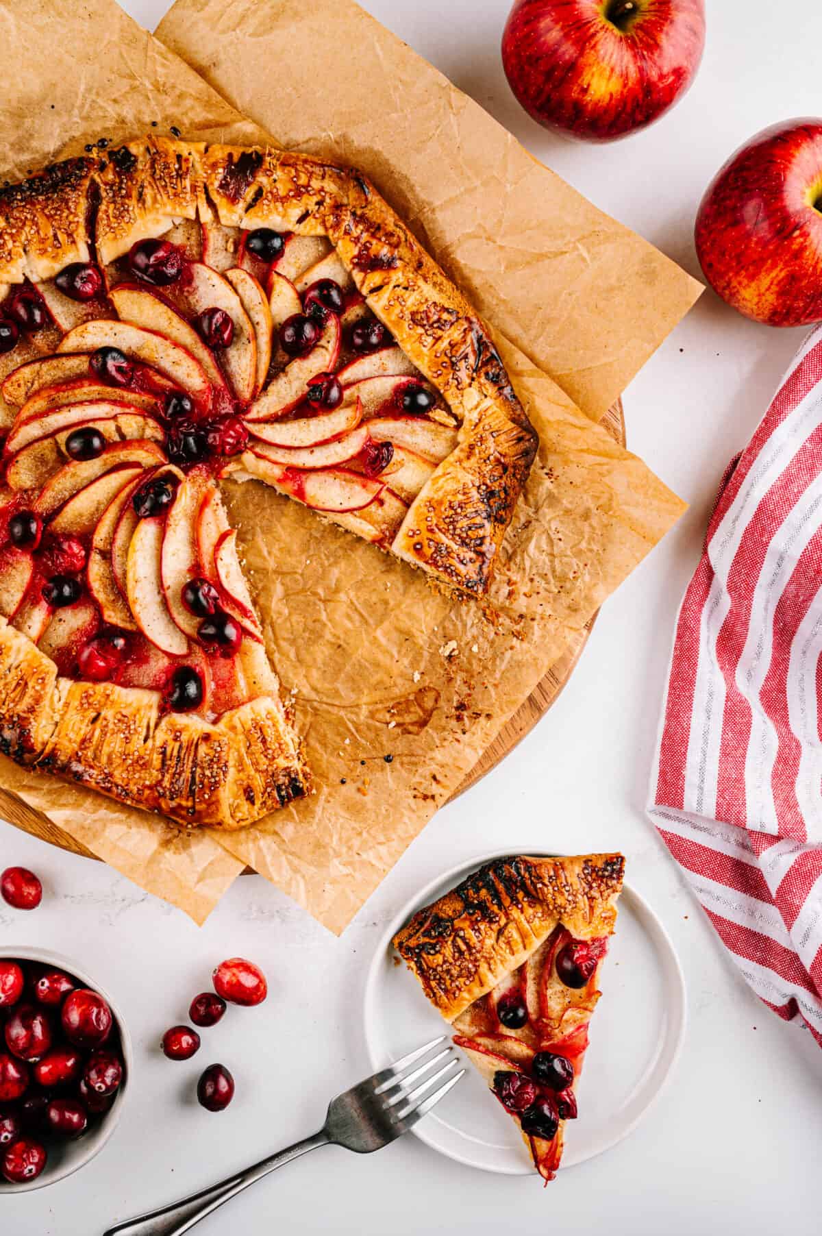 overhead shot of apple galette recipe on parchment paper and slice of galette on white plate