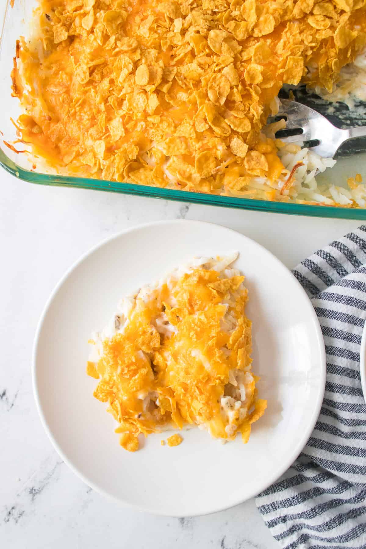 white plate with funeral potatoes and casserole dish of potatoes