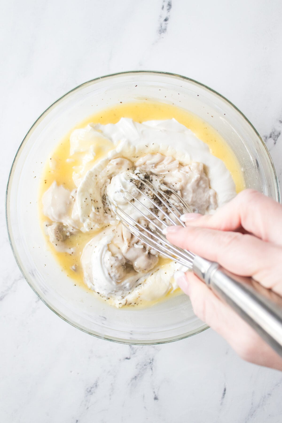 mixing sour cream, cream of mushroom soup and melted butter together with whisk in glass bowl