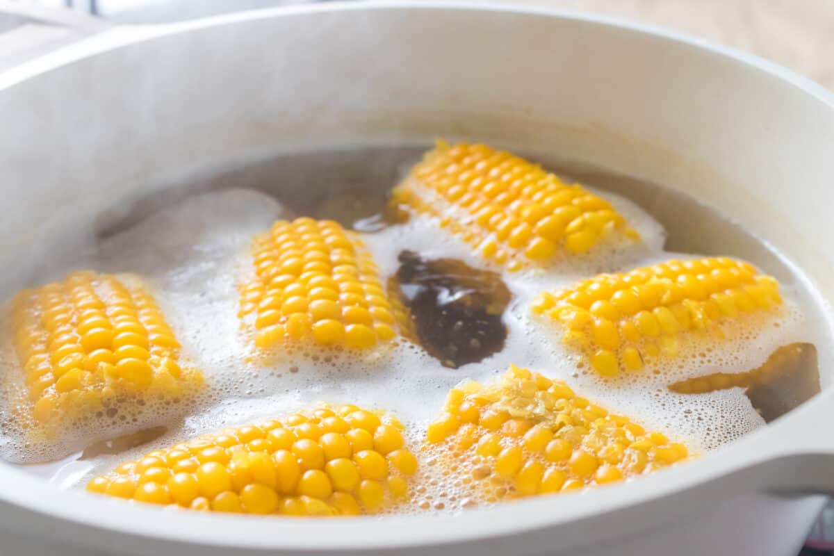 corn and red potatoes boiling in white pan