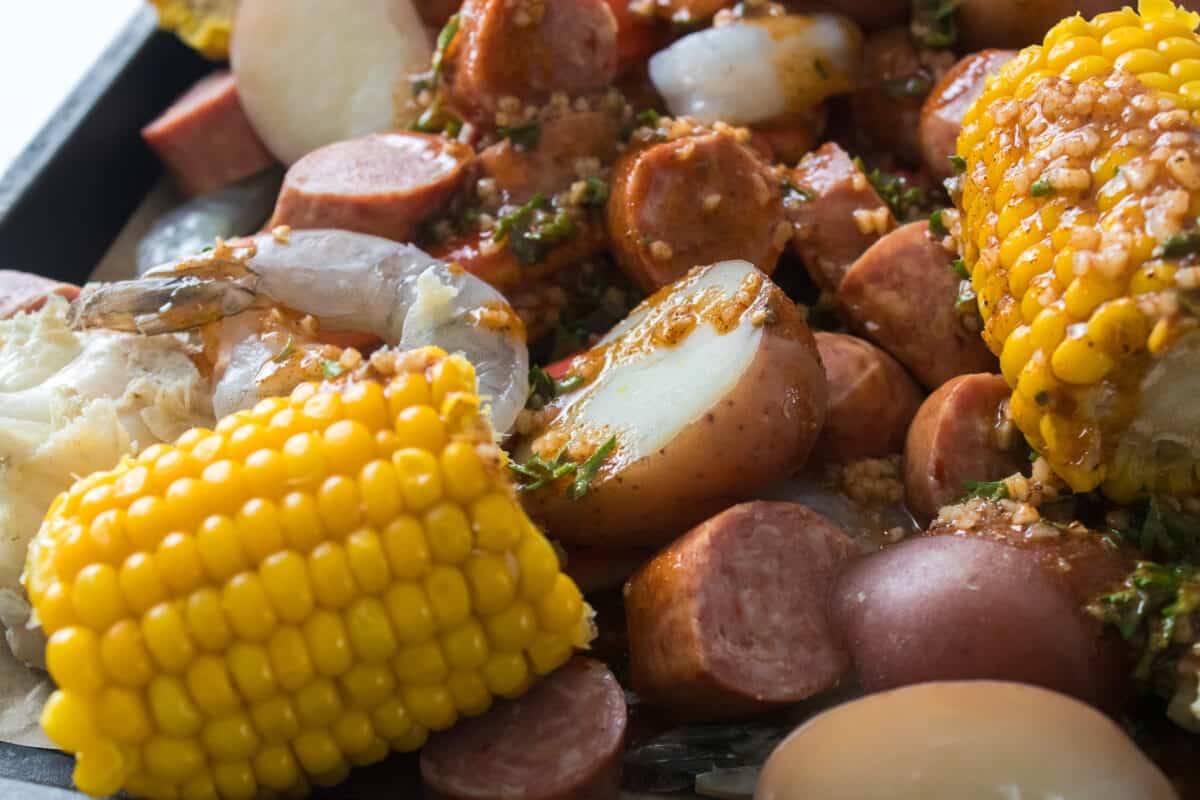 garlic butter mixture drizzled over sea food boil on baking sheet