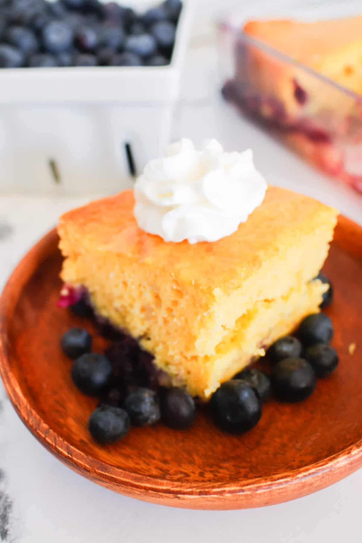 slice of blueberry lemon cake with blueberries in background