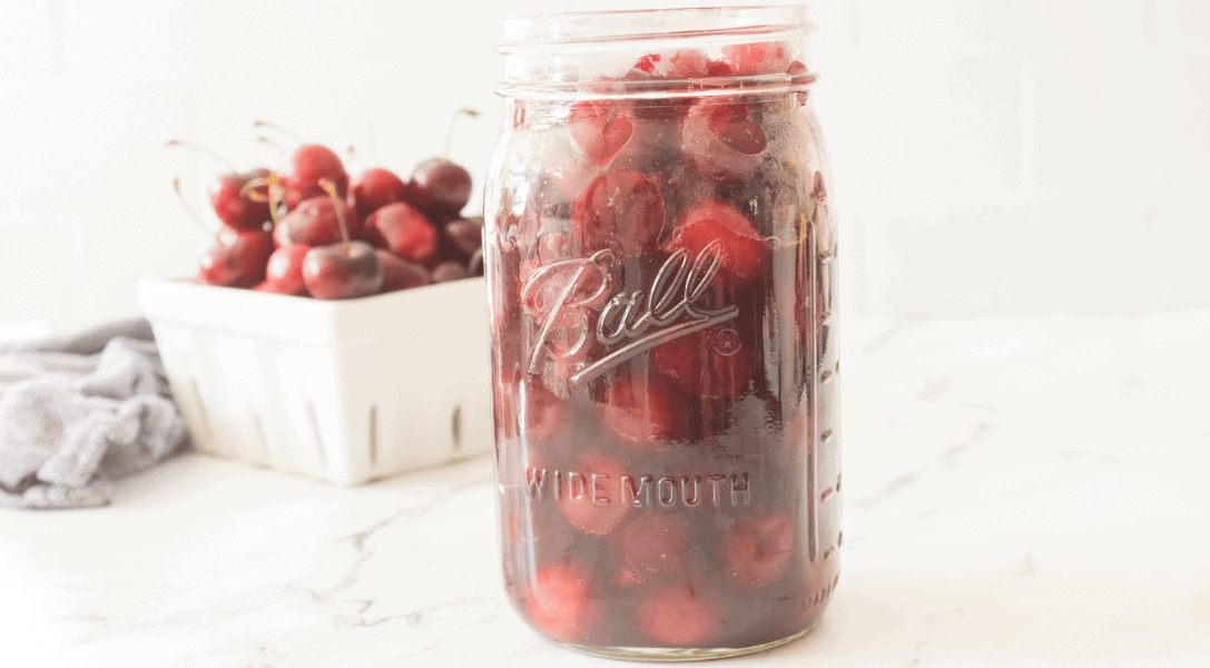 Cherry Pie Filling in mason jar with cherries in background