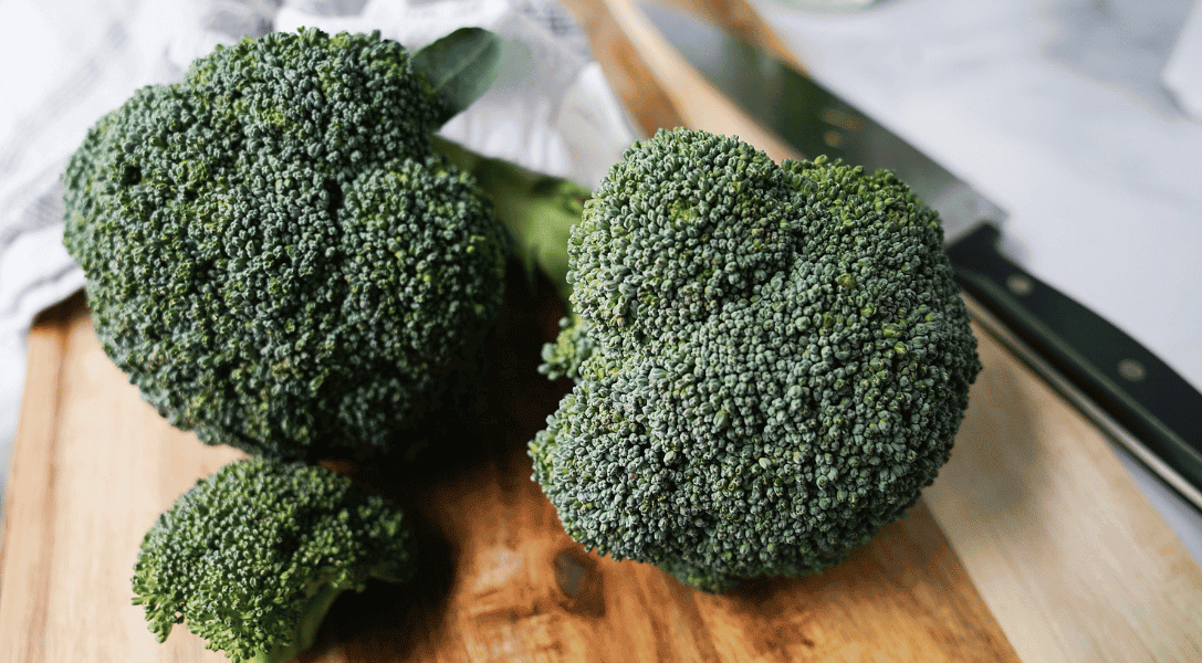 close up of broccoli florets on a wooden cutting board