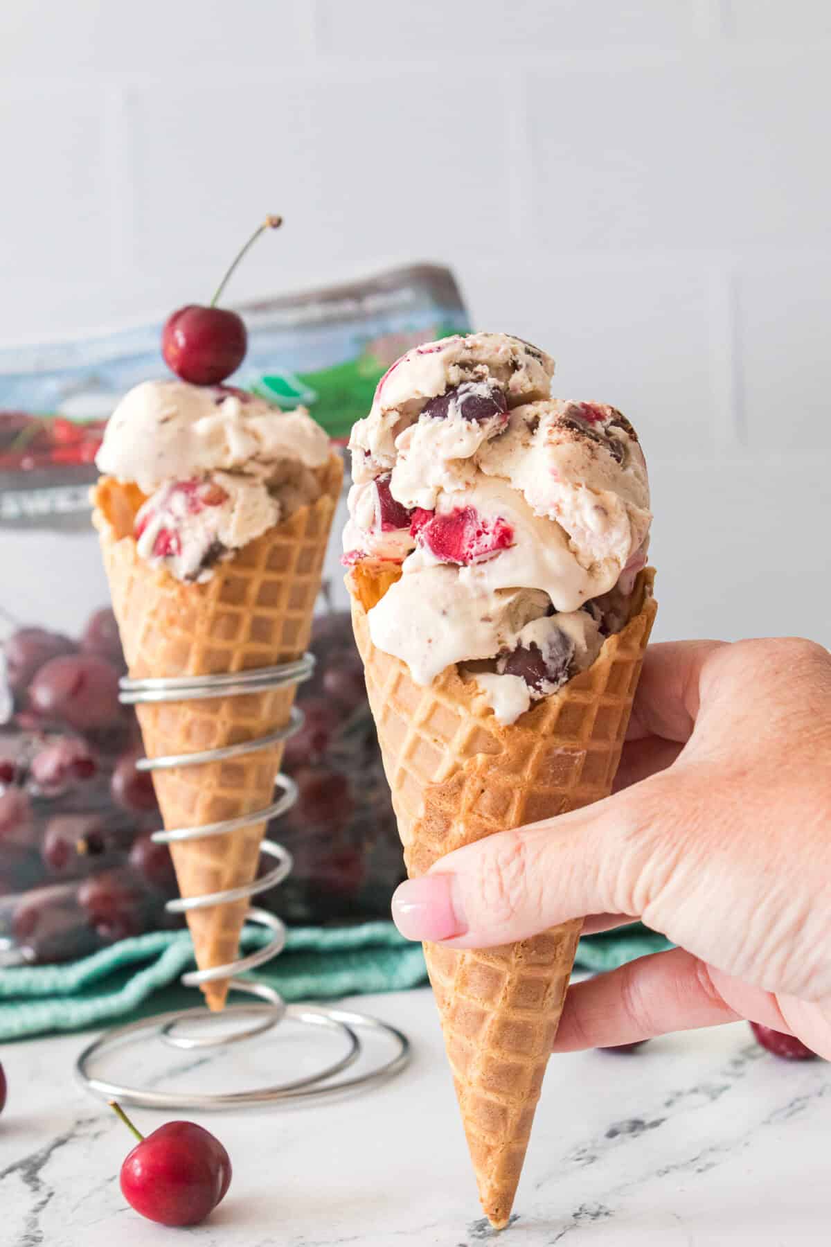 hand grabbing cherry garcia ice cream in a waffle cone
