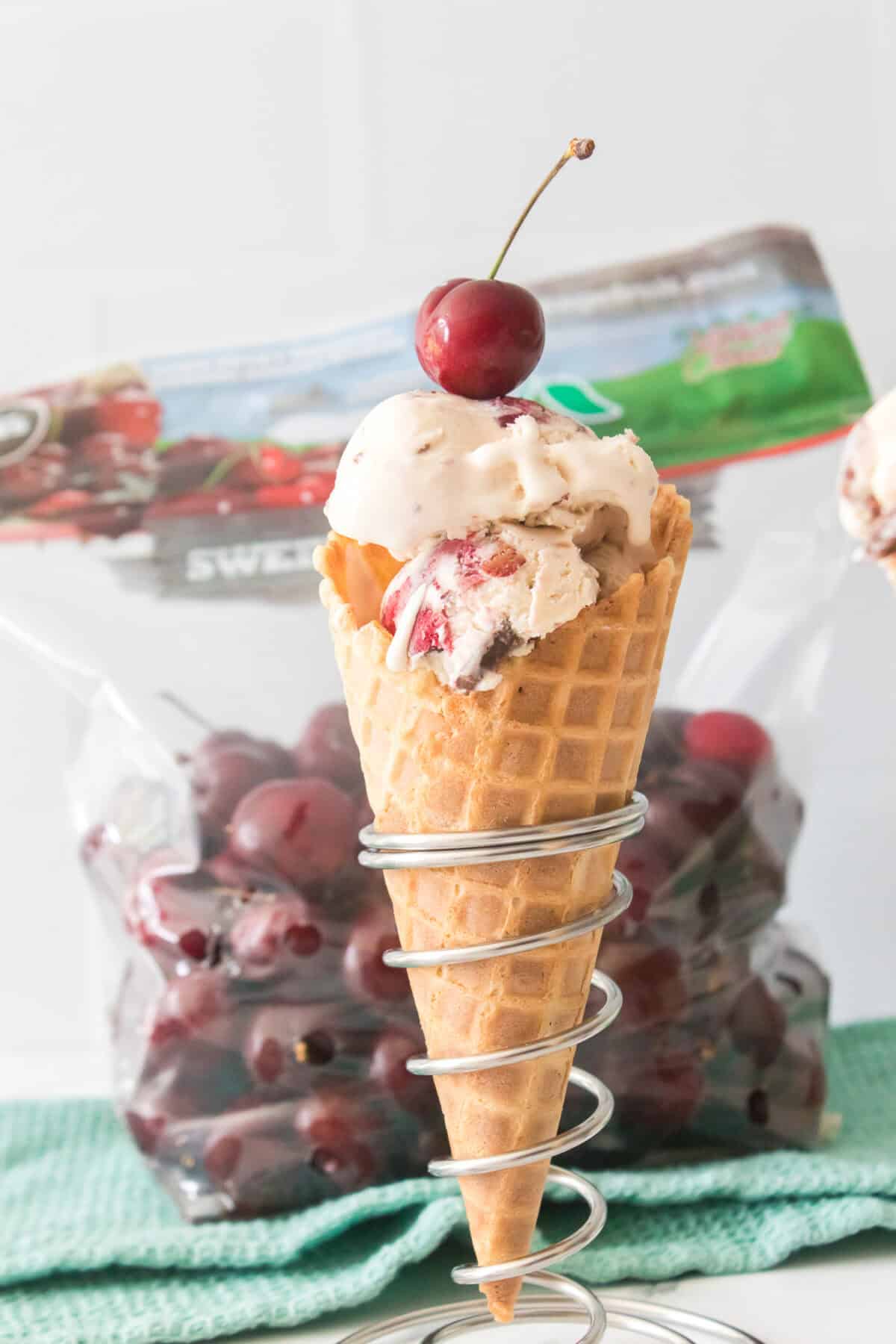 cherry garcia ice cream topped with a fresh cherry in a waffle cone