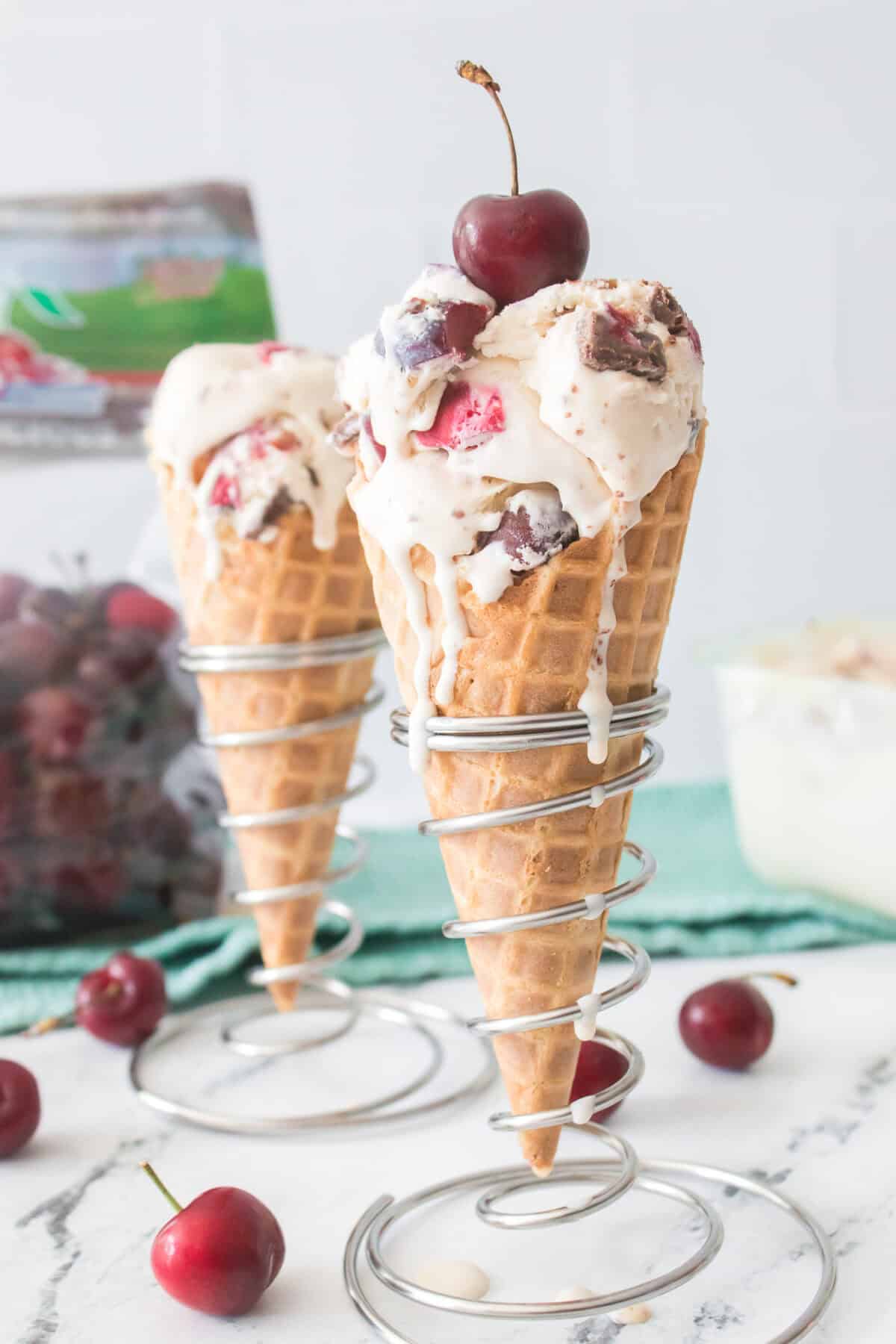close head on vertical image of cherry garcia ice cream melting down waffle cone that is topped with a cherry