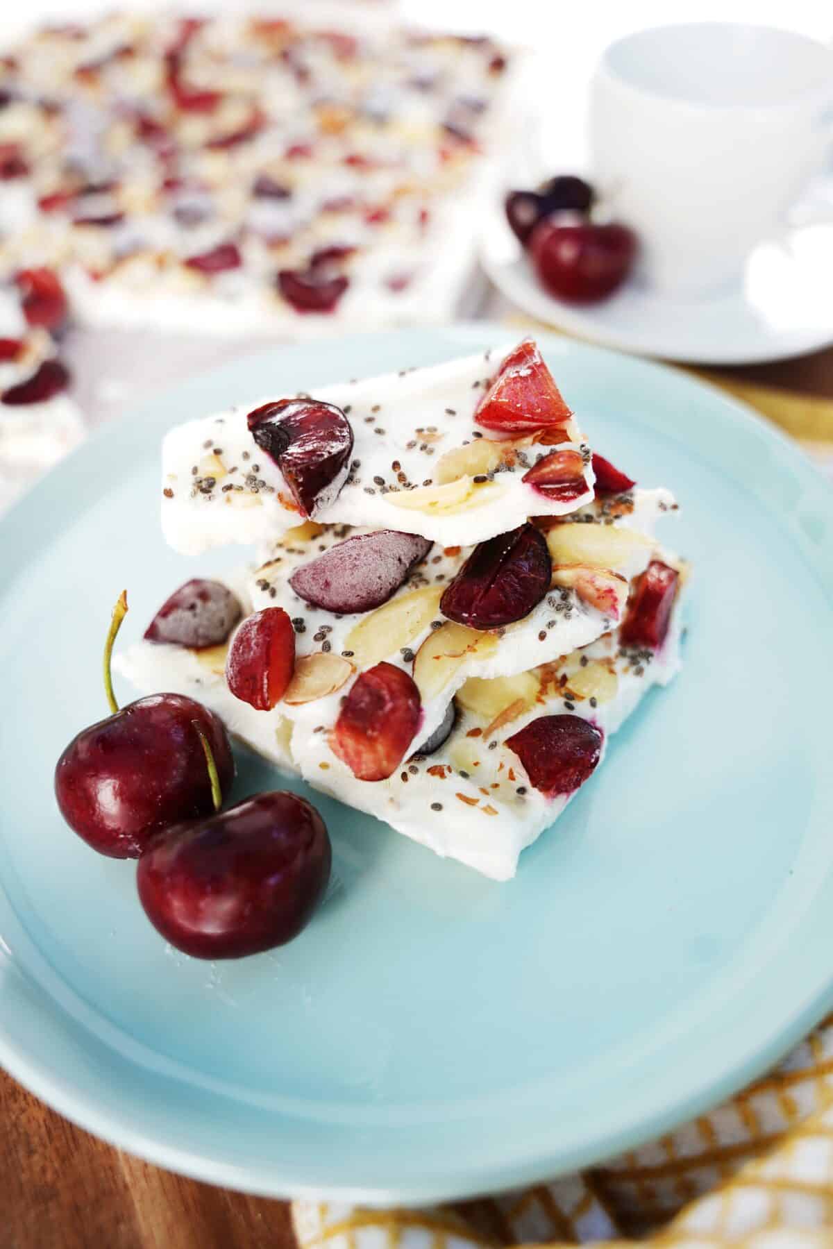 close up vertical image of cherry yogurt bark served on blue plate