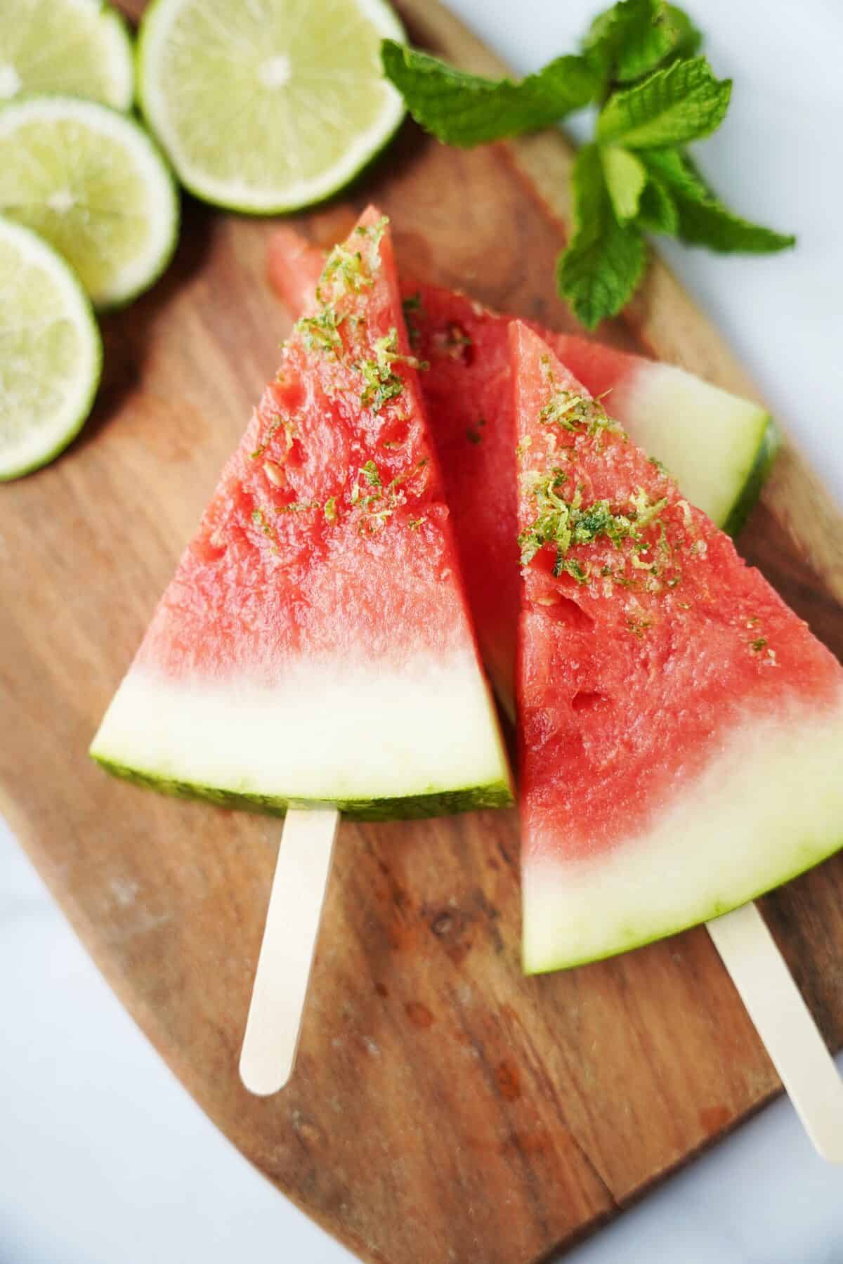 close up shot of margarita watermelon slices with popsicle sticks topped with lemon zest and salt