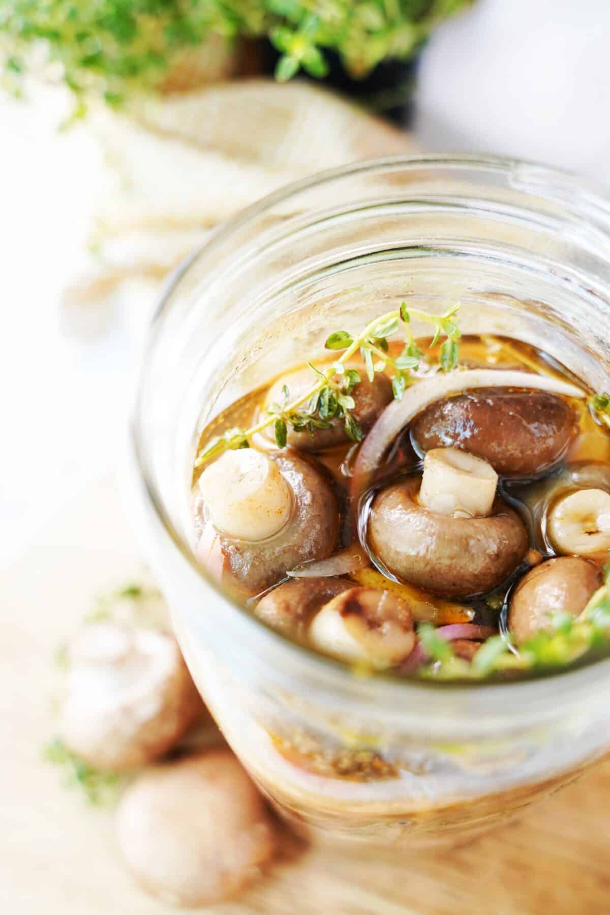 close up vertical shot of pickled mushrooms in mason jar