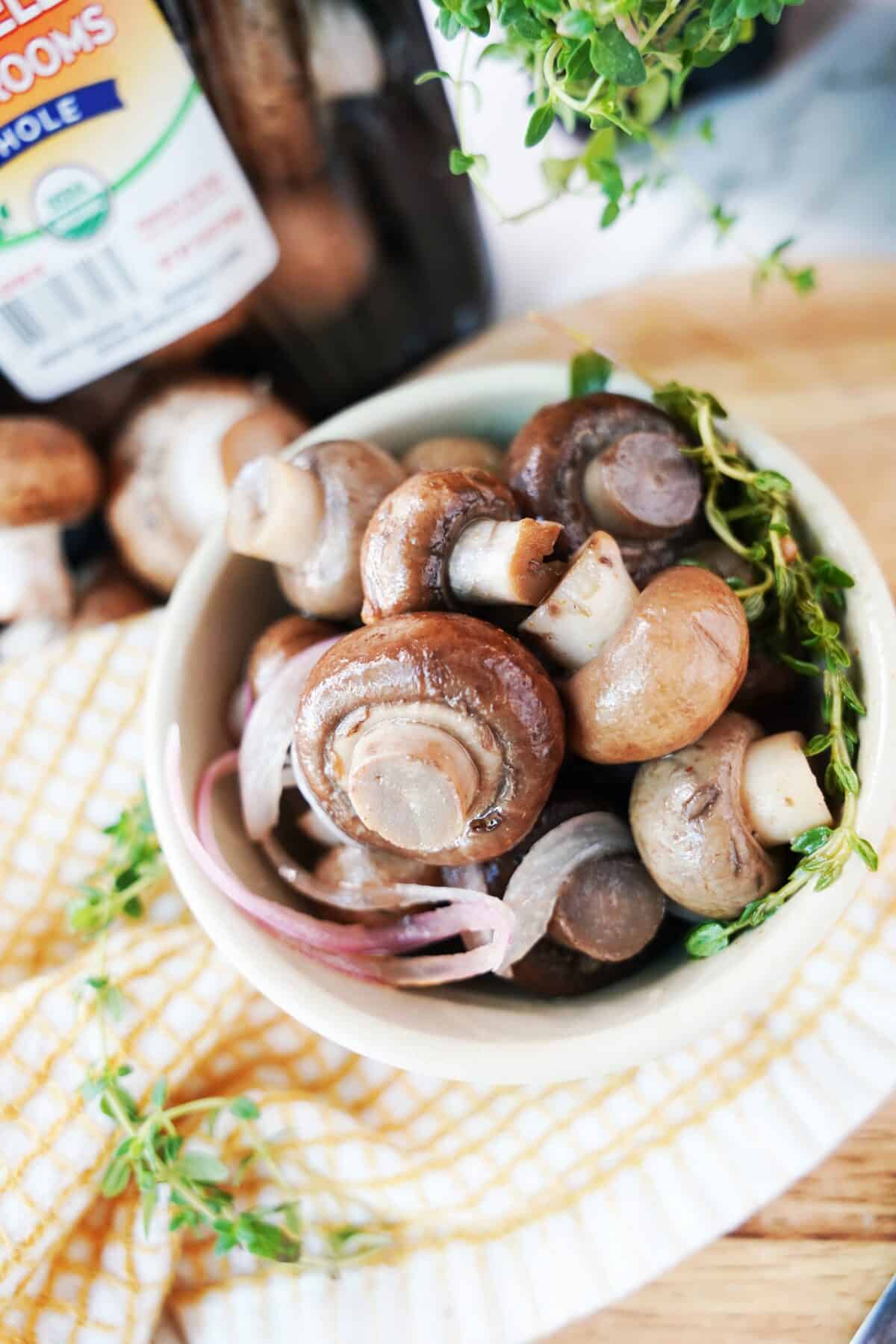 close up shot of pickled mushrooms with red onion in bowl