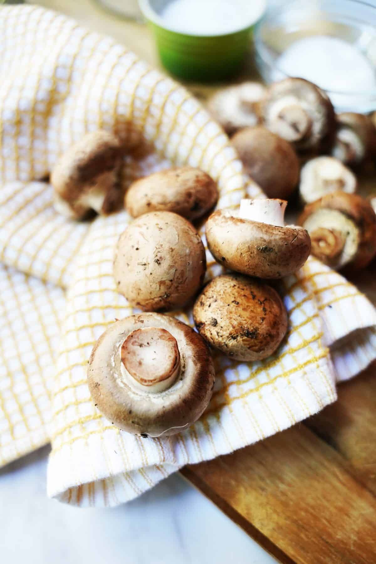 baby bella mushrooms being cleaned on dish towel