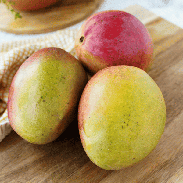 3 mangoes on a cutting board