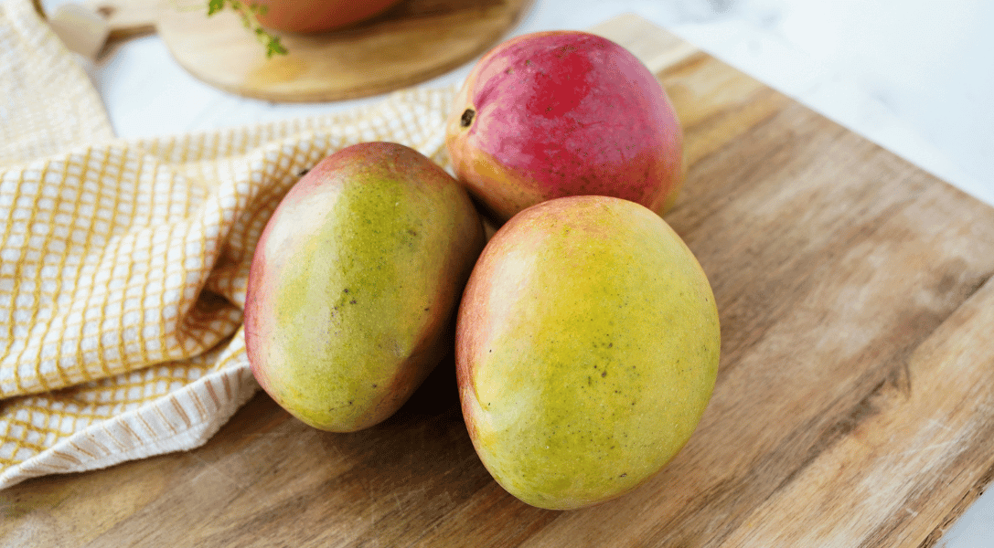 3 mangoes on a cutting board