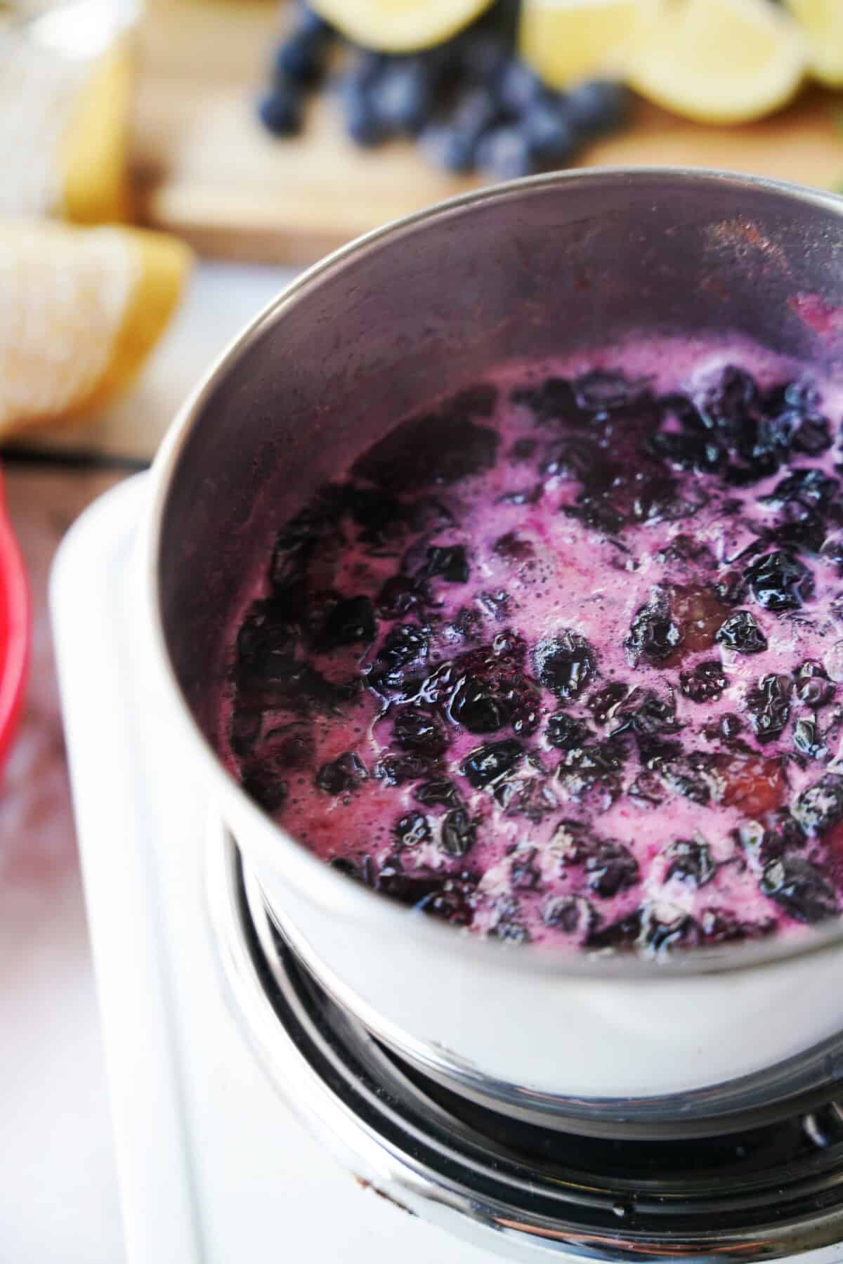 Blueberry simple syrup simmering in a saucepan.