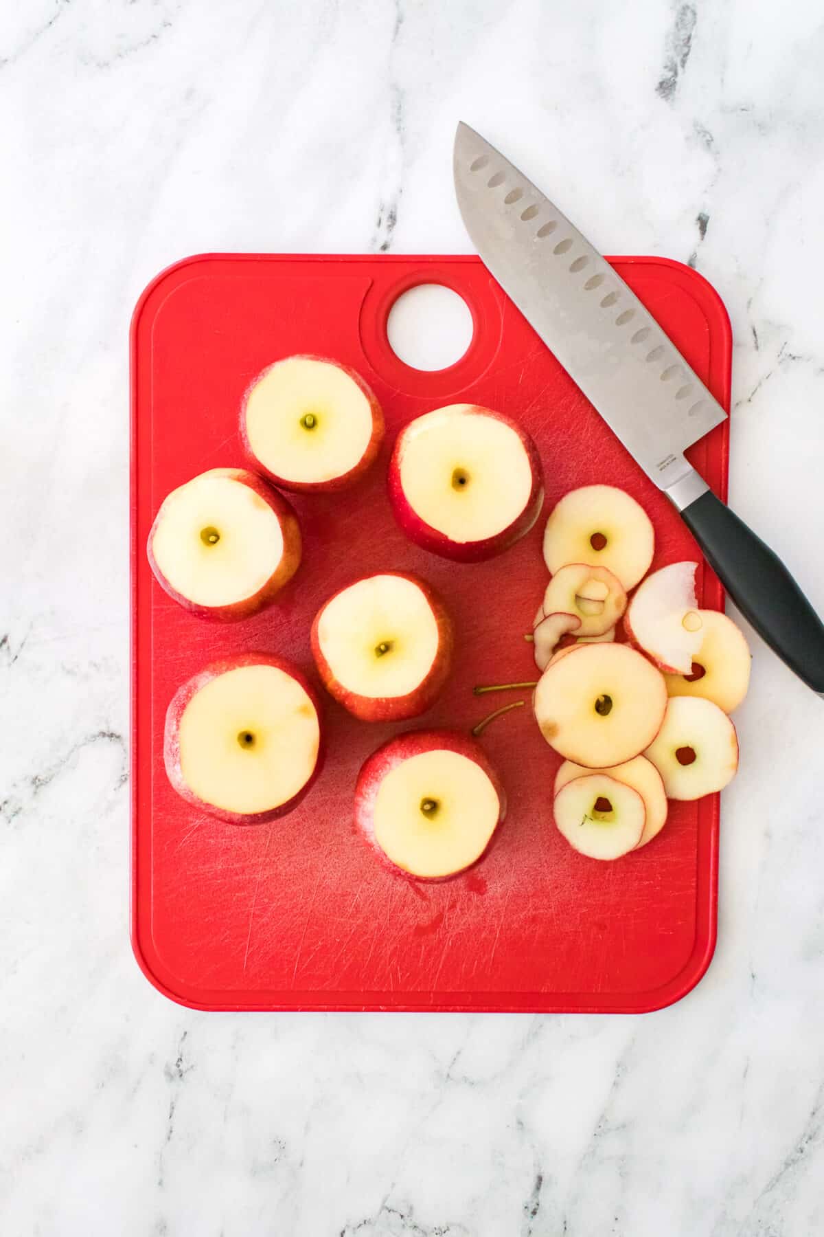 red cutting board with knife used to cut tops off