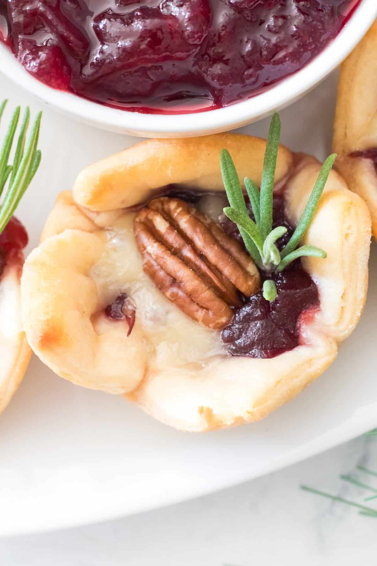 vertical overhead close up shot of cranberry brie bite on serving platter with cranberry sauce