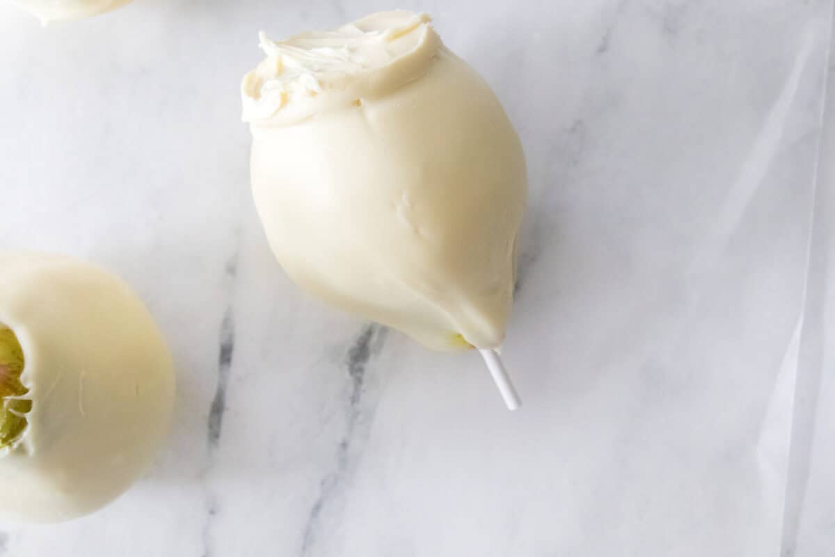 bartlett pear coated in melted white chocolate on wax paper